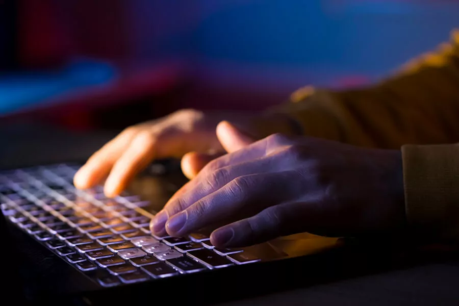 Hands typing on a back-lit keyboard